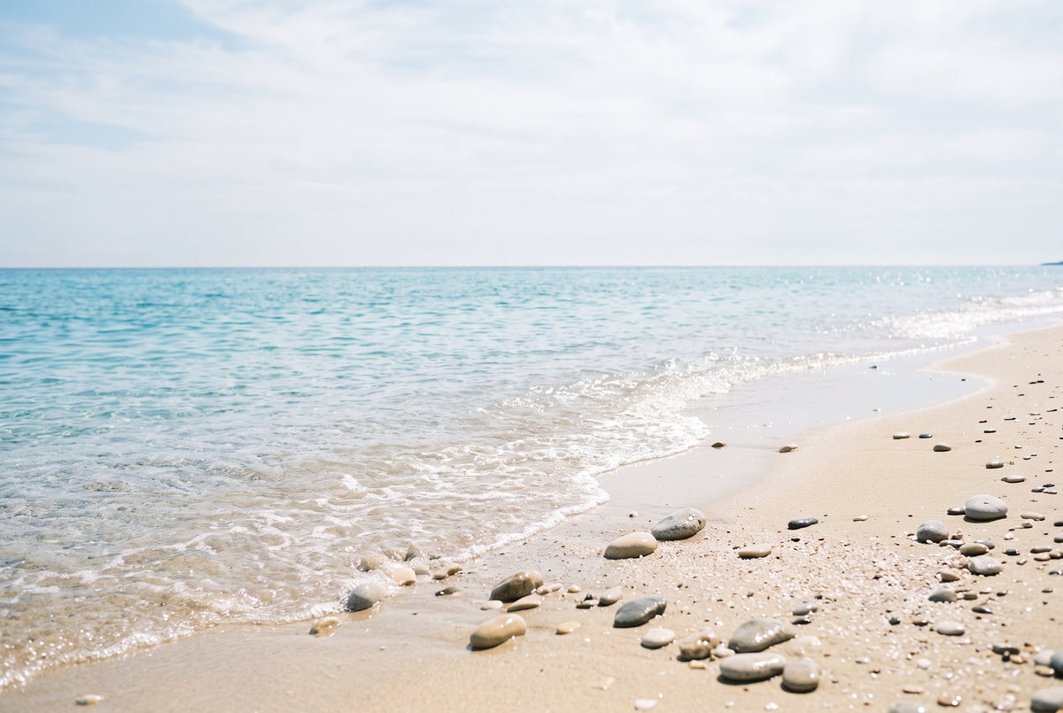 Türkises Meer trifft auf hellen Sandstrand mit Kieseln – Salzwasser tut Psoriasis-Haut gut