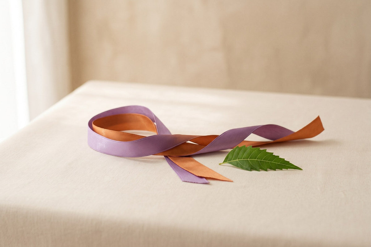Schleife in Lila und Orange, das Symbol des Welt-Psoriasis-Tags, neben einem Neemblatt auf hellem Hintergrund